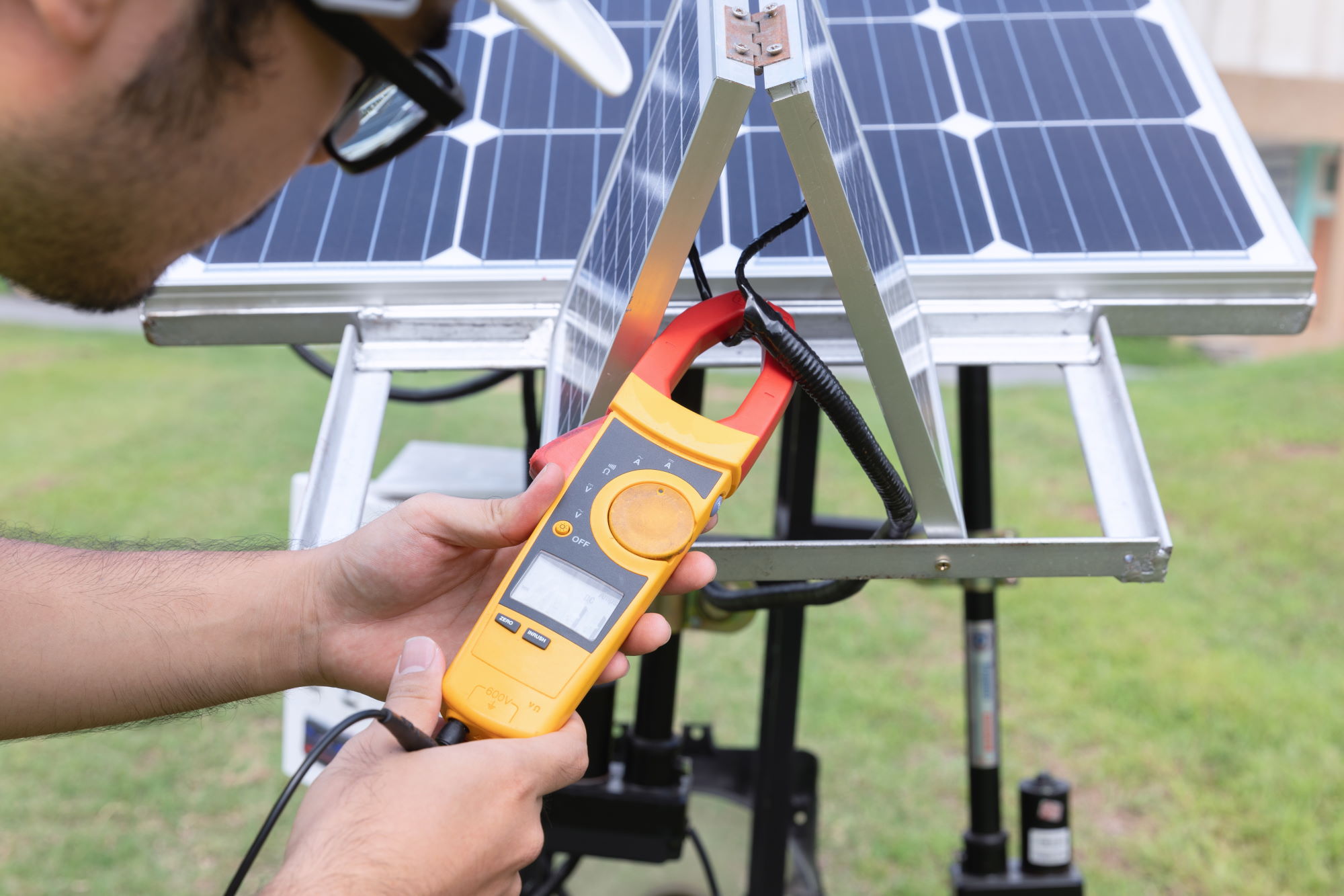 Engineer solar photovoltaic panels station checks with measurement tool.